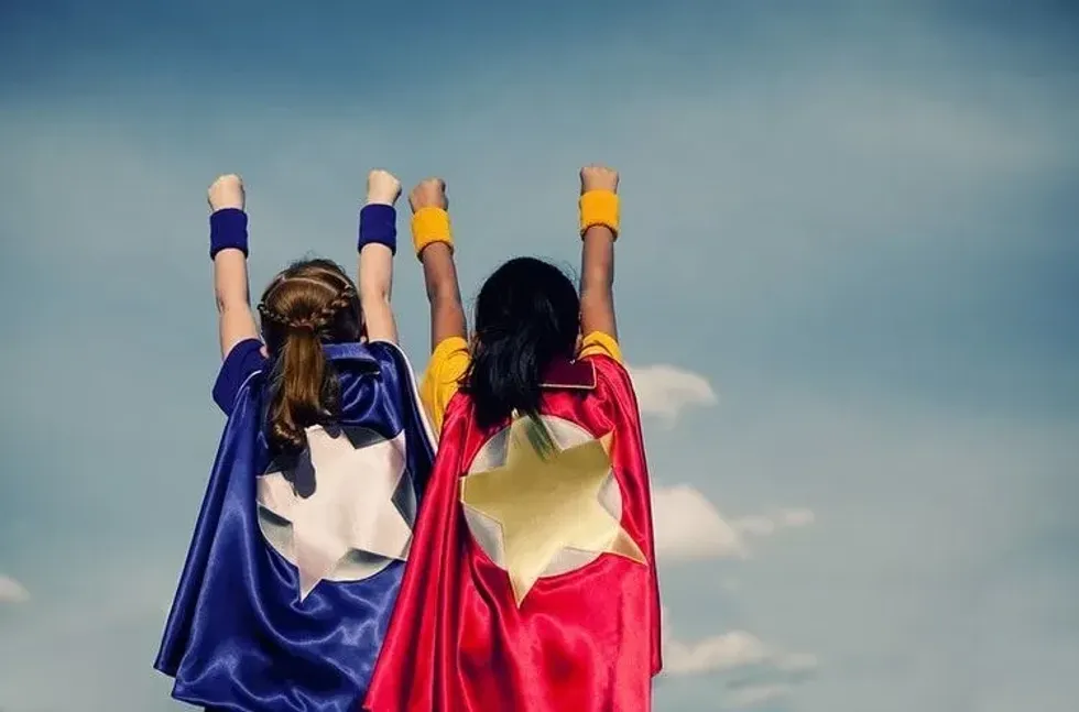 Two girls dressed and posing as superheroes