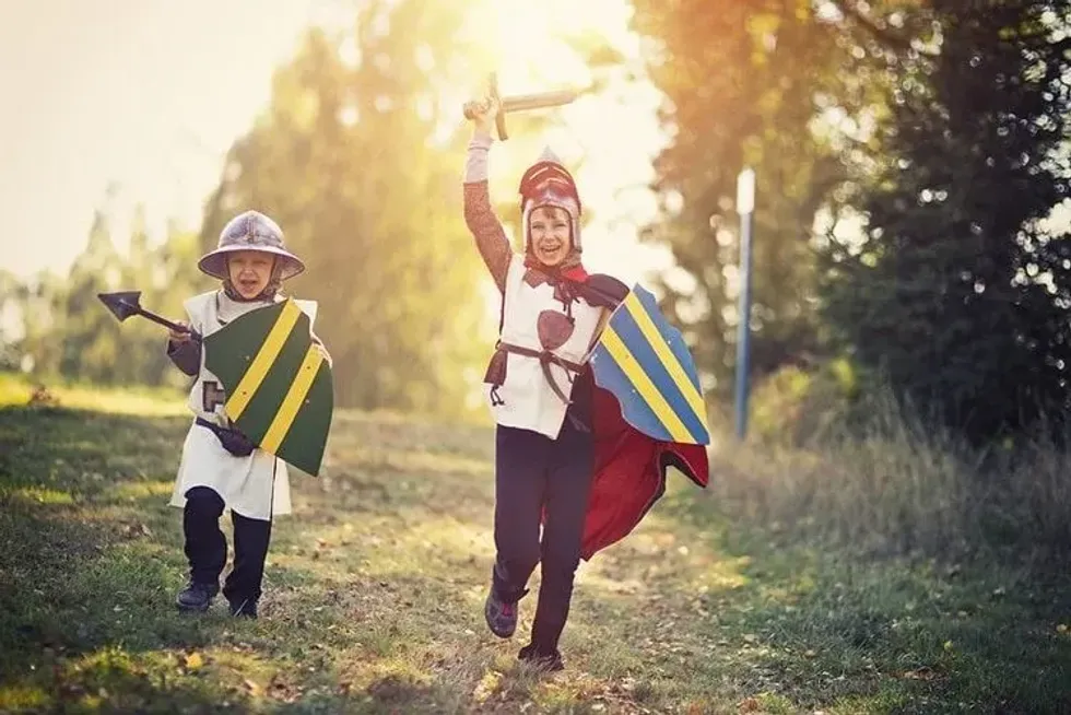 Two little boys dressed up as warriors carrying sword and shield