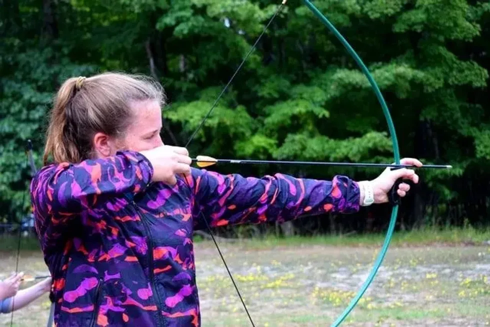 Woman archer with bow and arrow ready to shoot at a target